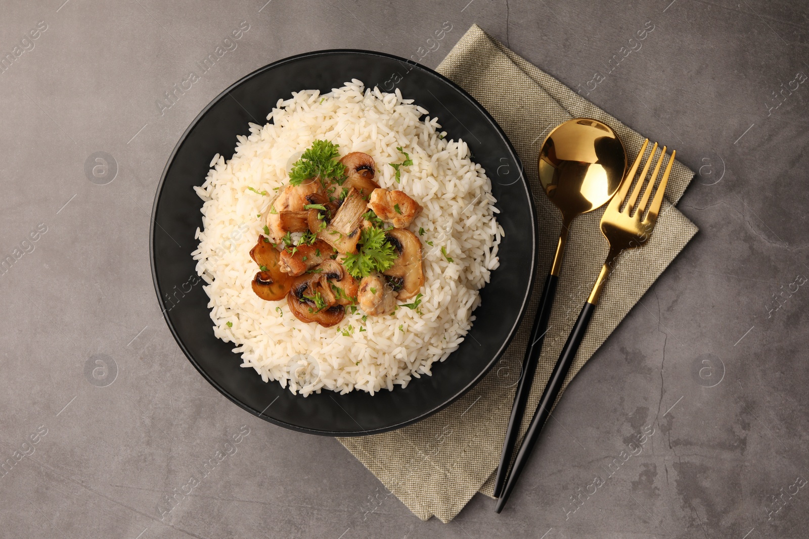 Photo of Delicious rice with parsley and mushrooms served on grey table, flat lay