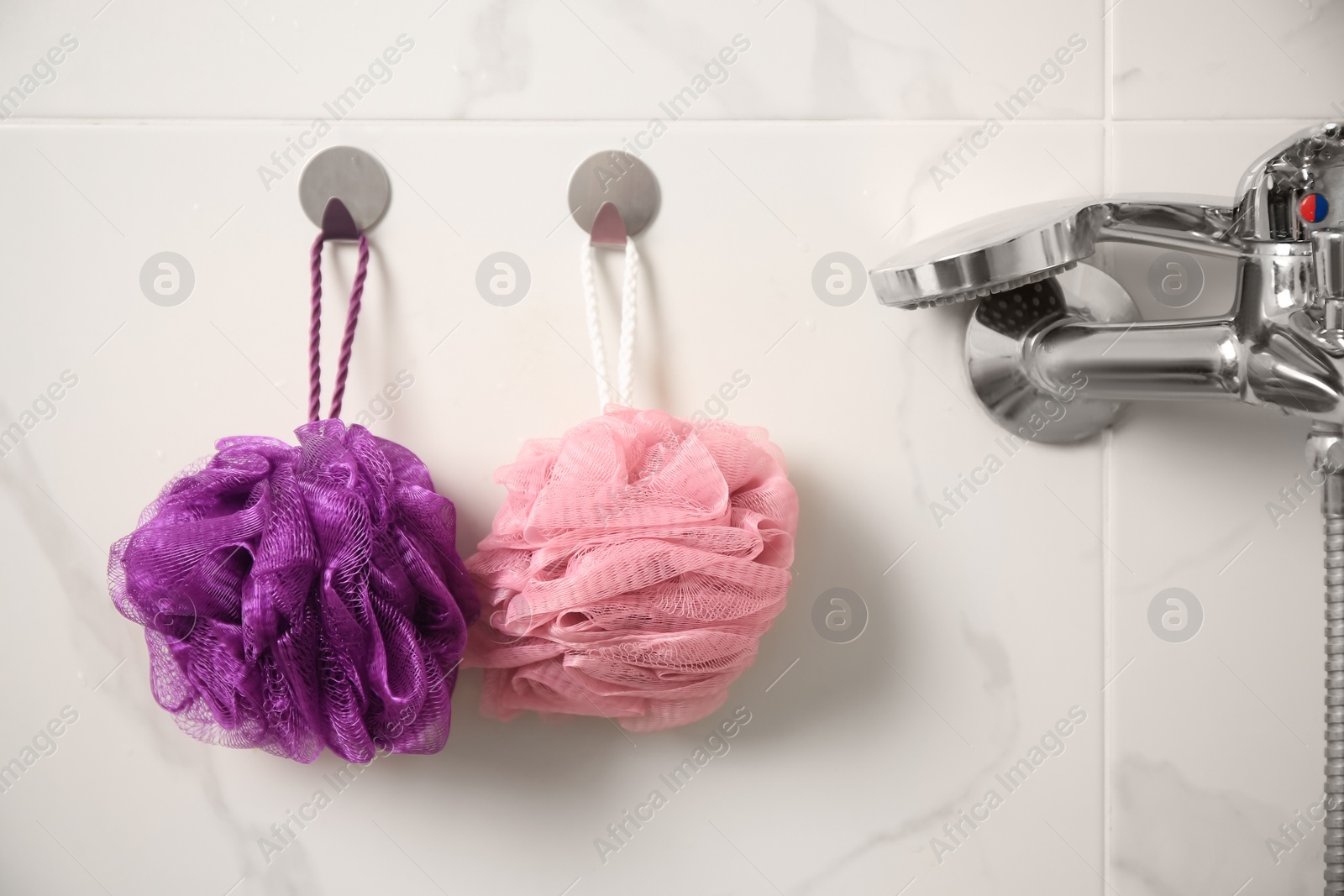 Photo of Shower puffs hanging near faucet in bathroom