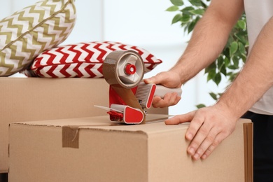 Photo of Man packing carton box indoors, closeup. Moving day