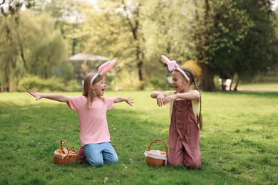 Easter celebration. Cute little girls in bunny ears with wicker baskets outdoors