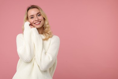 Happy woman in stylish warm sweater on pink background. Space for text