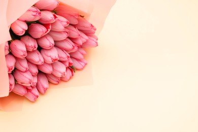 Photo of Bouquet of beautiful pink tulips on beige background, above view. Space for text