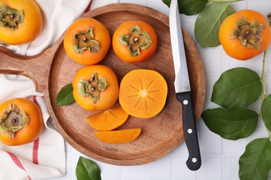 Photo of Delicious ripe persimmons and knife on white table, flat lay