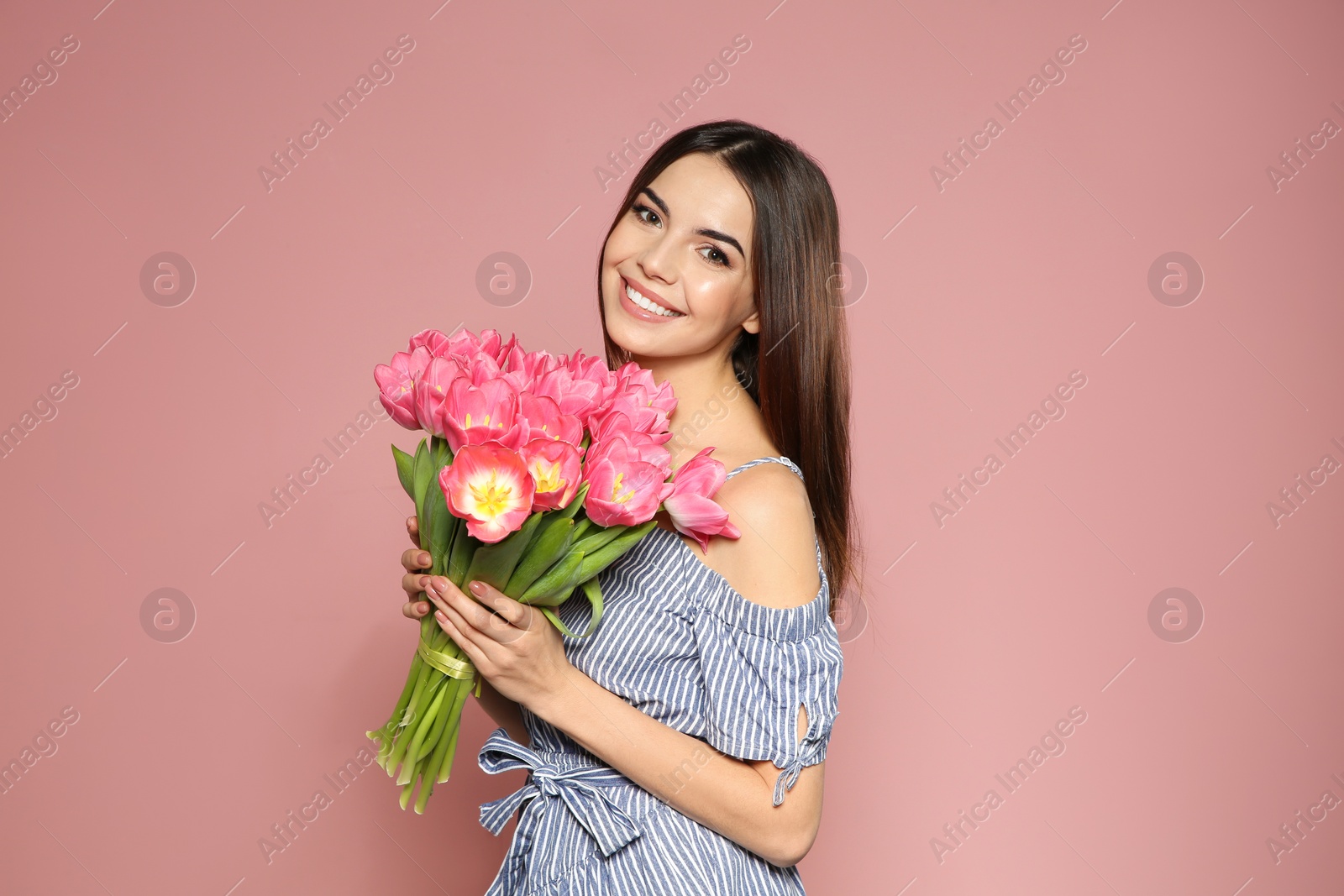 Photo of Portrait of beautiful smiling girl with spring tulips on pink background. International Women's Day