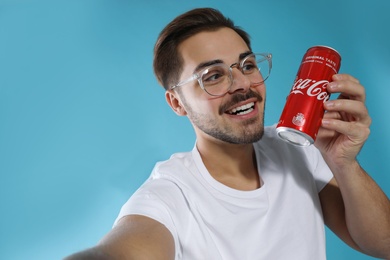 MYKOLAIV, UKRAINE - NOVEMBER 28, 2018: Young man taking selfie with Coca-Cola can on color background