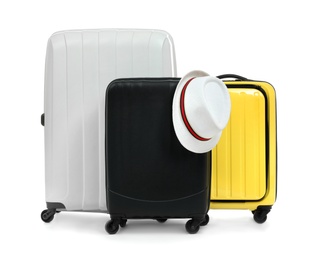 New suitcases and hat packed for journey on white background