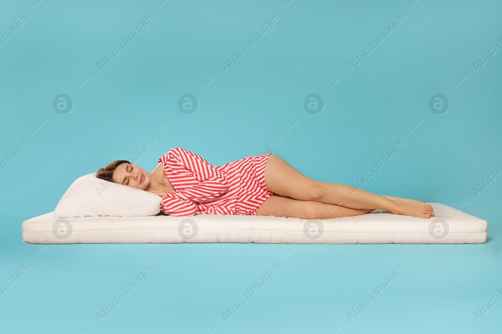 Photo of Young woman sleeping on soft mattress against light blue background