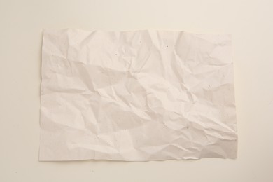 Sheet of crumpled parchment paper on beige background, top view