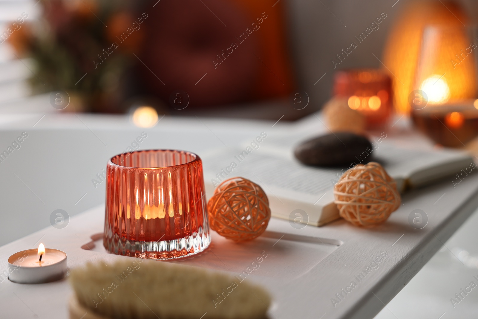 Photo of White wooden tray with burning candles on bathtub in bathroom, closeup