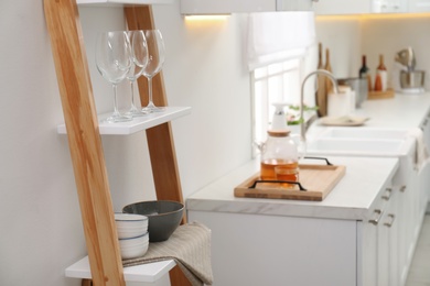Photo of Stylish kitchen room interior with wooden ladder near white wall