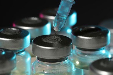 Photo of Filling syringe with medicine from vial against dark background, closeup