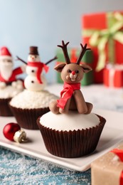 Photo of Different beautiful Christmas cupcakes on blue table with snow, closeup