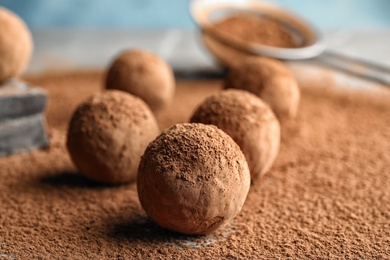 Photo of Sweet raw chocolate truffles powdered with cocoa on table