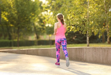 Photo of Young woman running in park on sunny day