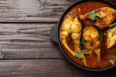 Photo of Tasty fish curry on wooden table, top view. Space for text. Indian cuisine