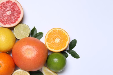 Photo of Different cut and whole citrus fruits on white table, flat lay. Space for text