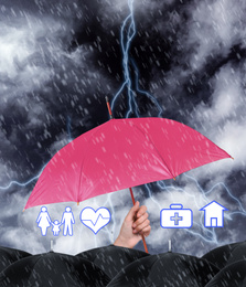 Image of Insurance agent covering illustrations with pink umbrella during storm