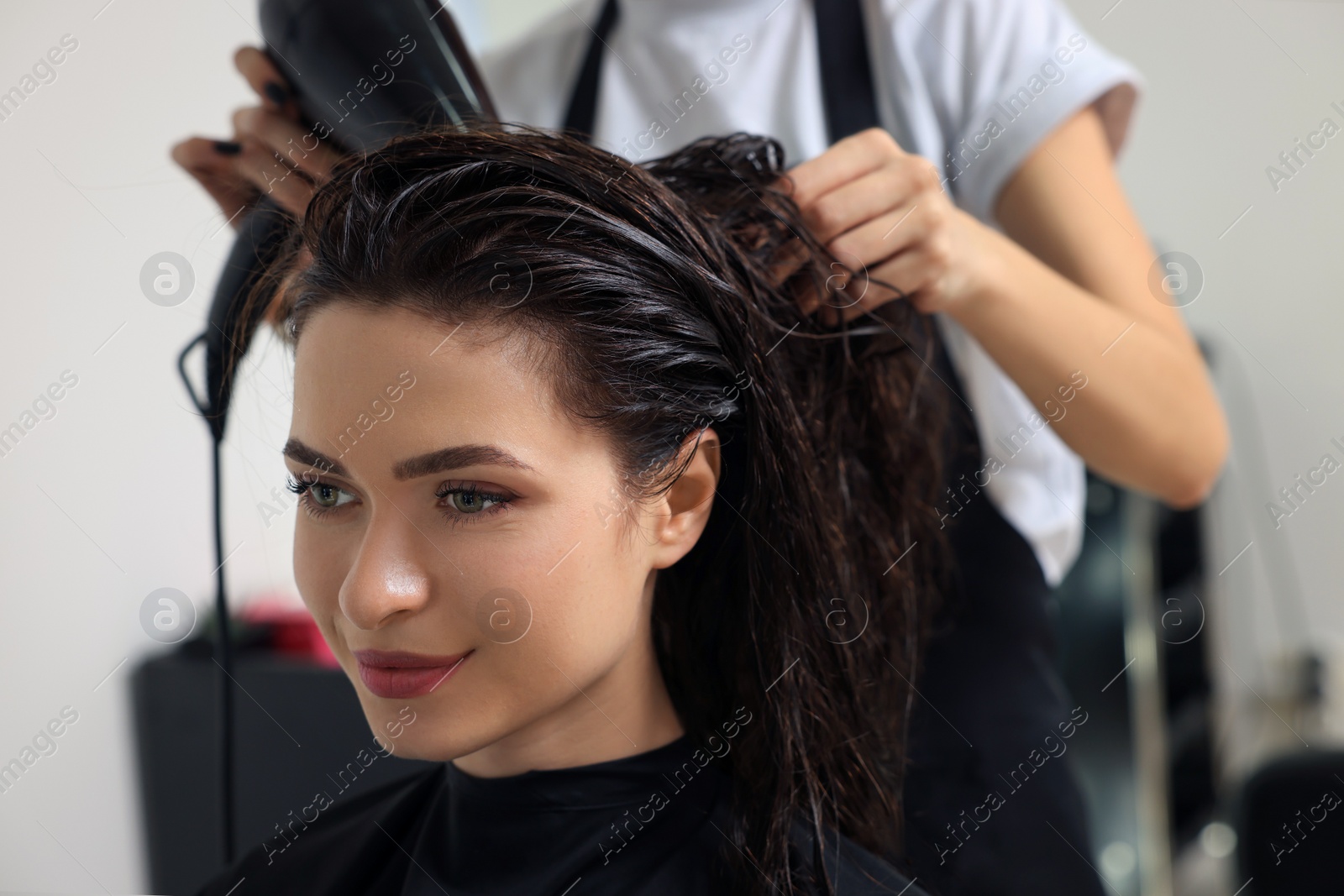 Photo of Hairdresser drying woman's hair in beauty salon