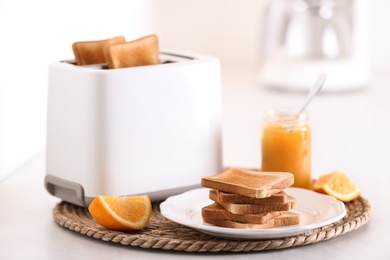 Modern toaster and delicious breakfast on table in kitchen