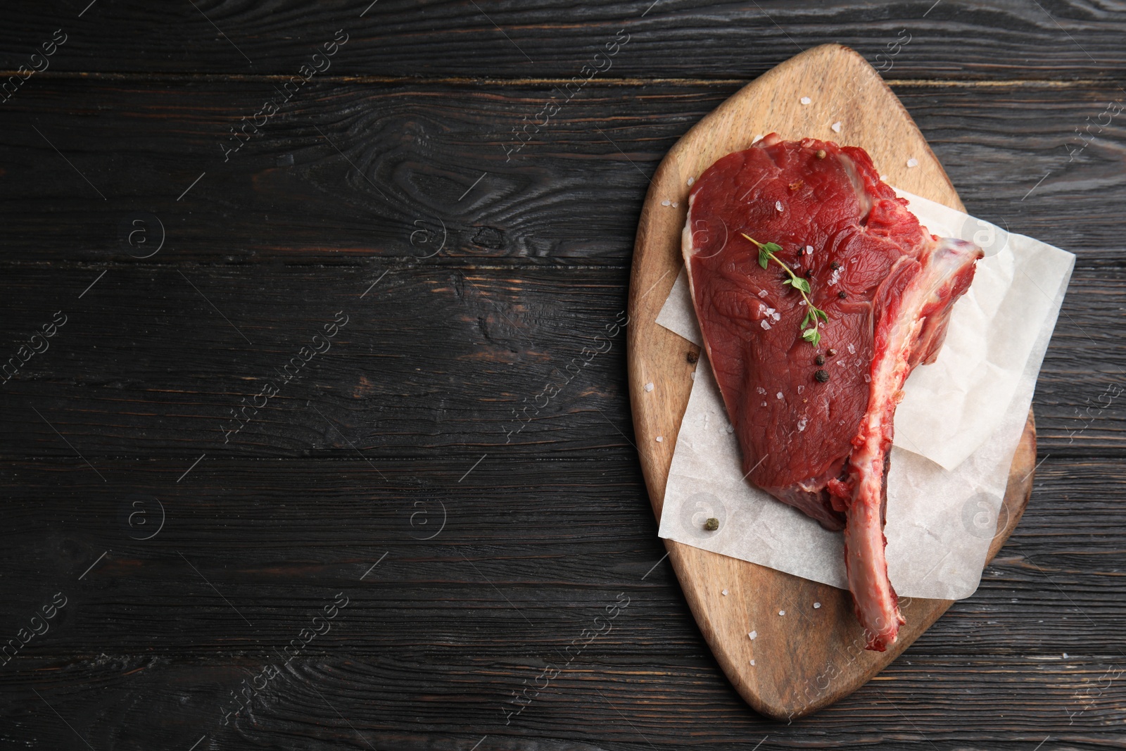 Photo of Fresh raw beef cut on wooden table, top view. Space for text