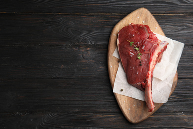 Photo of Fresh raw beef cut on wooden table, top view. Space for text