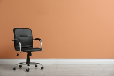 Photo of Modern office chair near orange coral wall indoors. Space for text