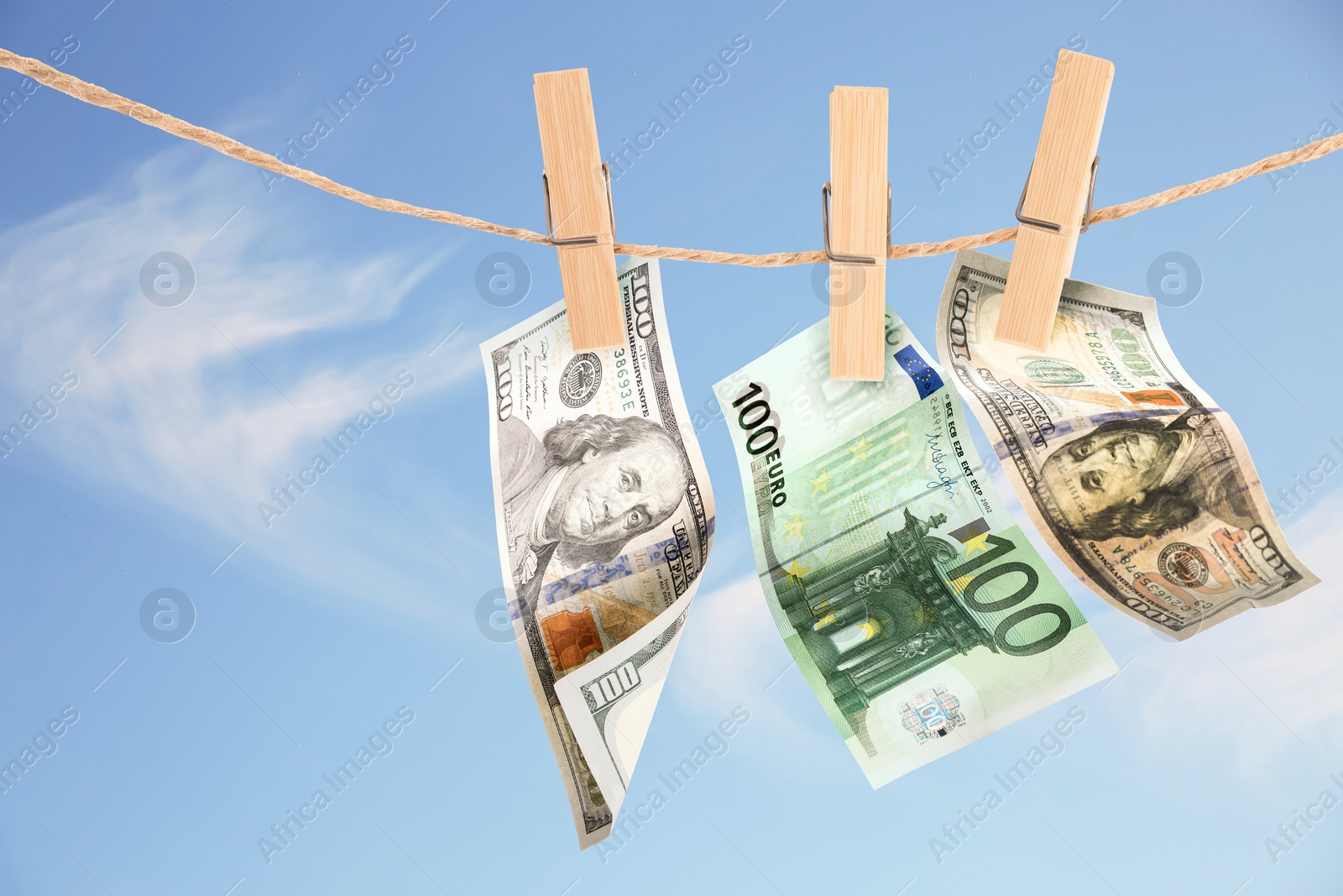 Image of Money laundering. Banknotes hanging on clothesline against blue sky