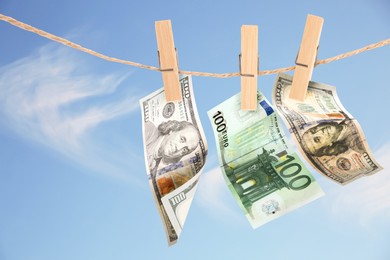 Money laundering. Banknotes hanging on clothesline against blue sky