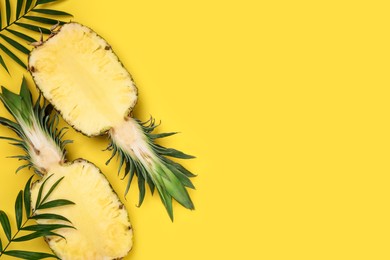 Photo of Halves of ripe pineapple and green leaves on yellow background, flat lay. Space for text