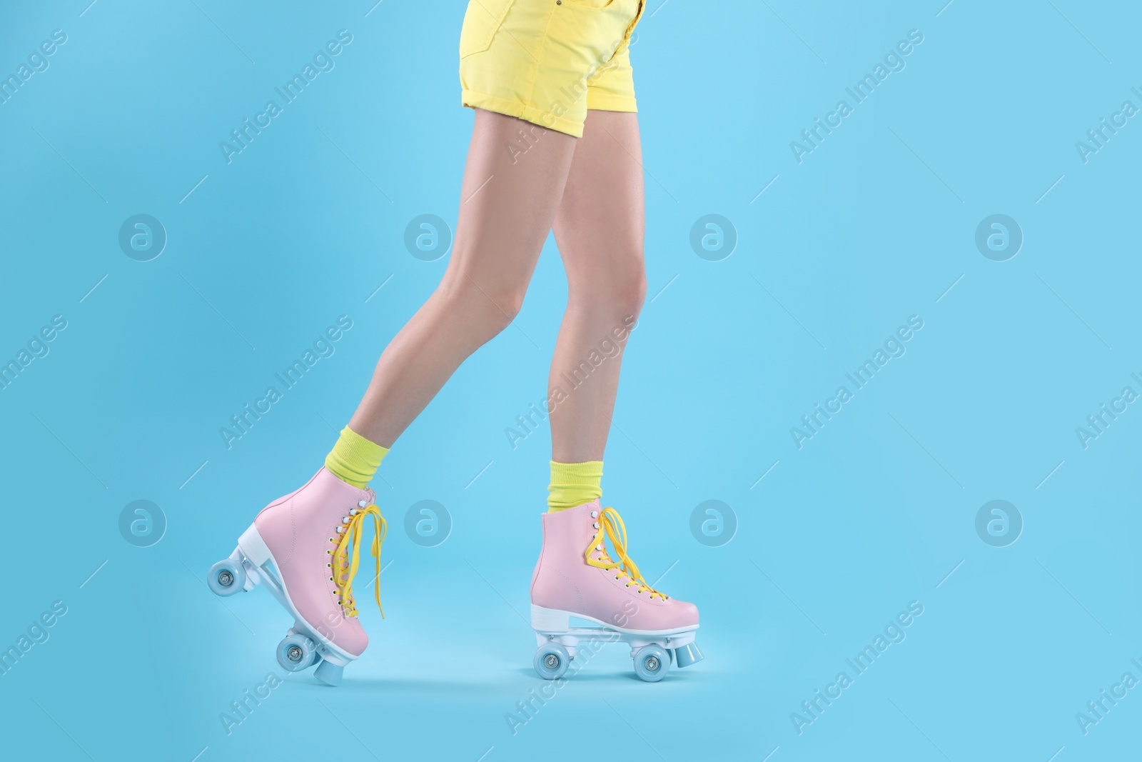 Photo of Young woman with retro roller skates on color background, closeup