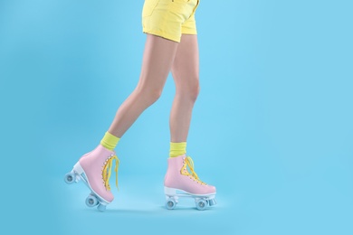 Photo of Young woman with retro roller skates on color background, closeup