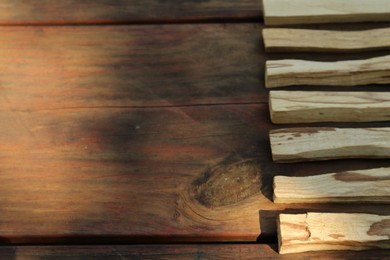 Photo of Palo santo sticks on wooden table, space for text