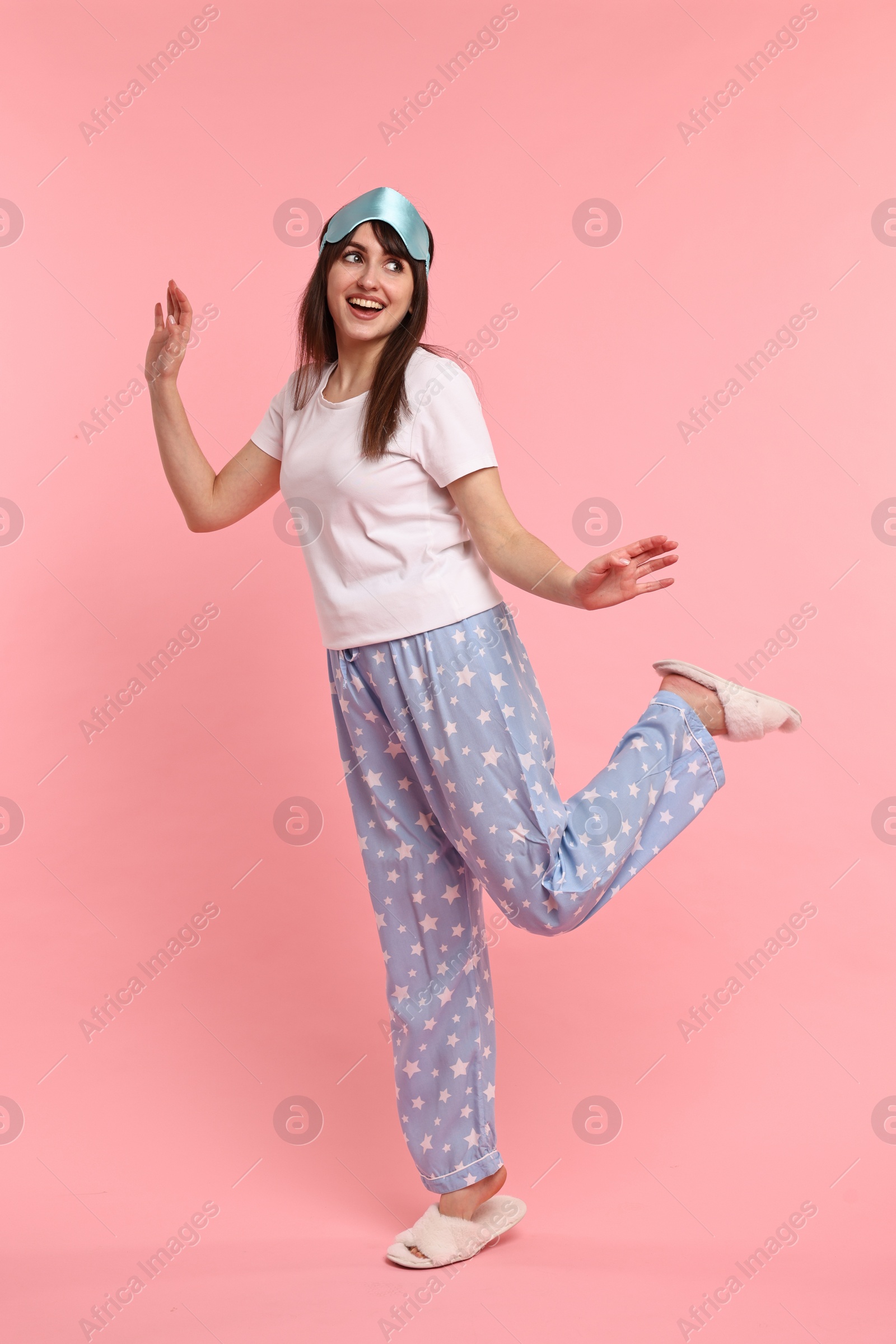 Photo of Happy woman in pyjama and sleep mask on pink background