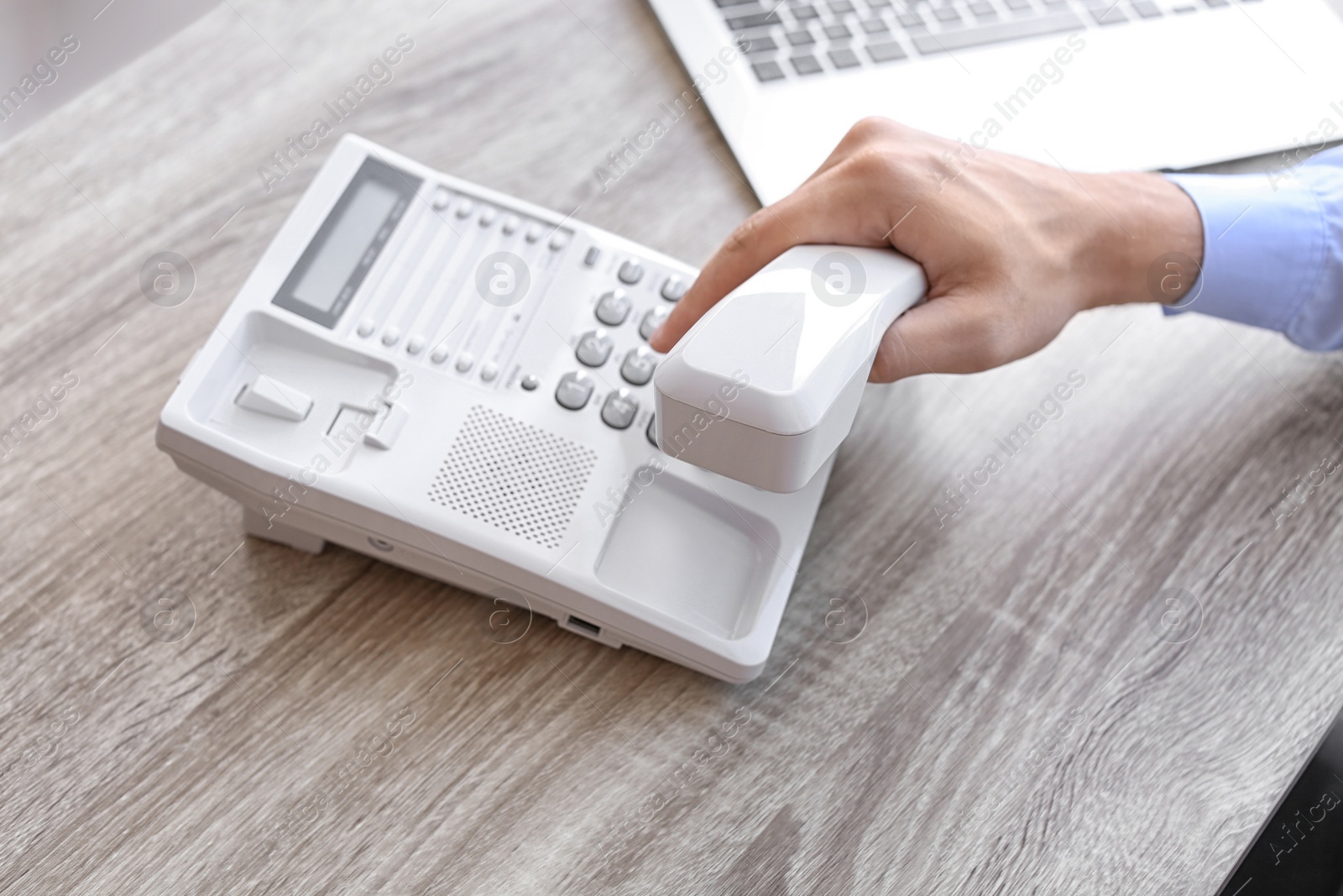 Photo of Man dialing number on telephone at workplace