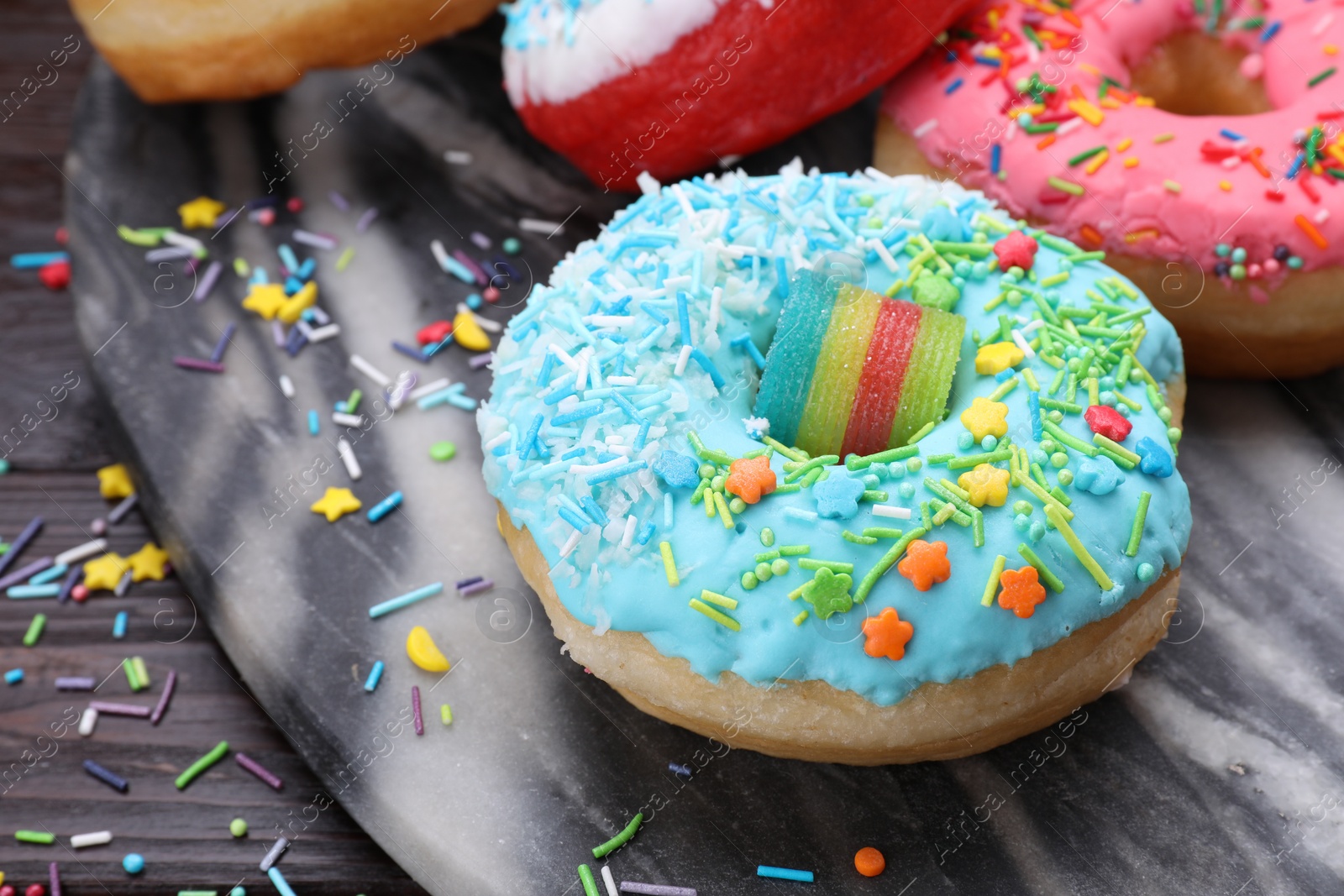 Photo of Sweet glazed donuts decorated with sprinkles on table, space for text. Tasty confectionery