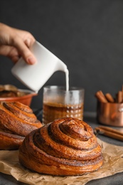 Photo of Parchment with freshly baked cinnamon rolls on table