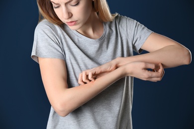 Photo of Woman scratching forearm on color background, closeup. Allergy symptom