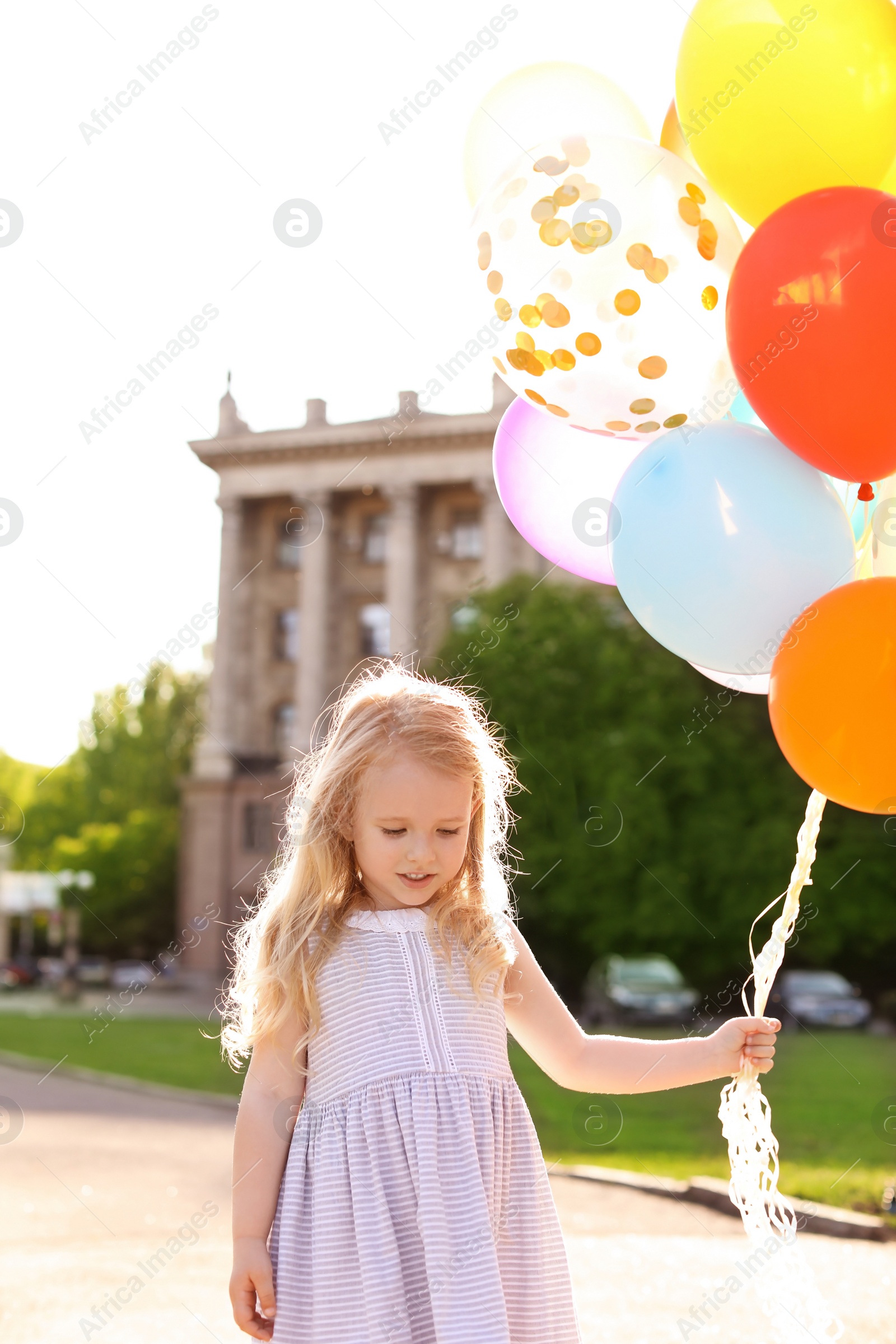 Photo of Cute little girl with colorful balloons outdoors on sunny day