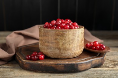 Photo of Cranberries in bowl and spoon on wooden table