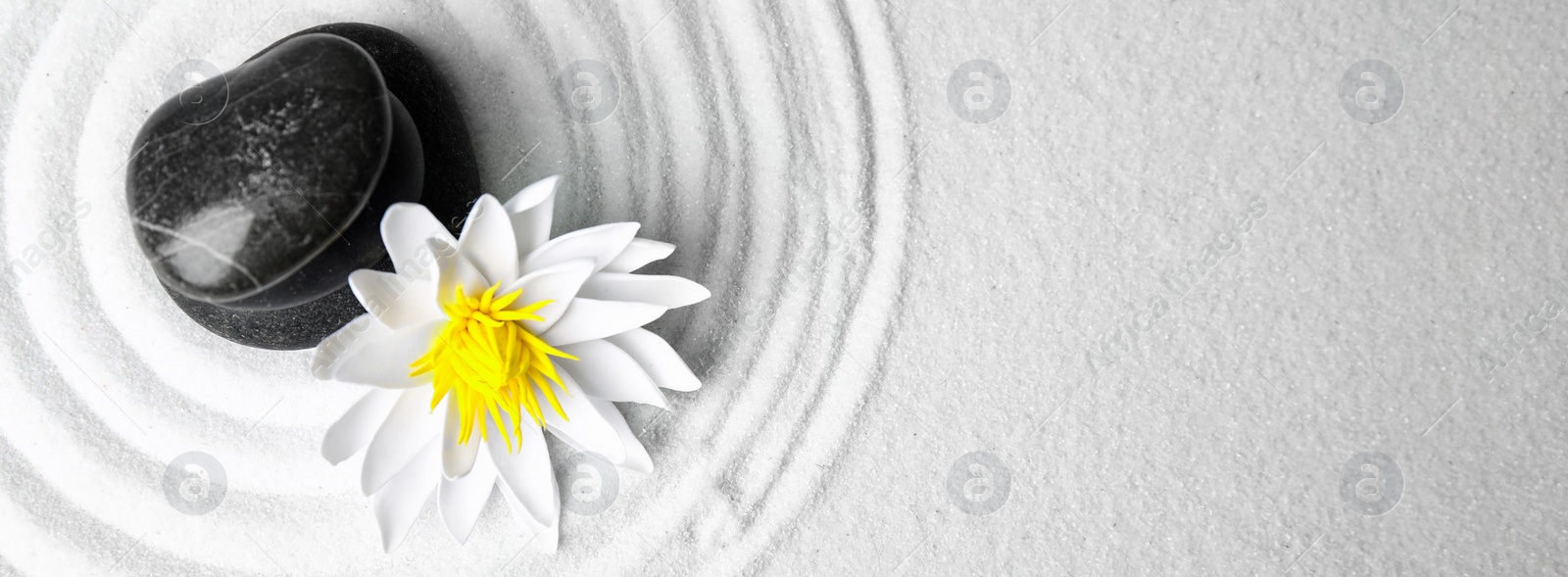 Image of Spa treatment. Flat lay composition with stone and lotus flower on white sand, space for text. Banner design