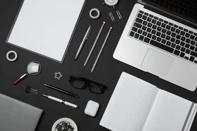 Photo of Flat lay composition with laptop and stationery on black background. Designer's workplace