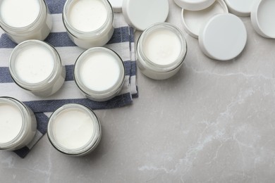 Tasty yogurt in glass jars on light grey marble table, flat lay. Space for text