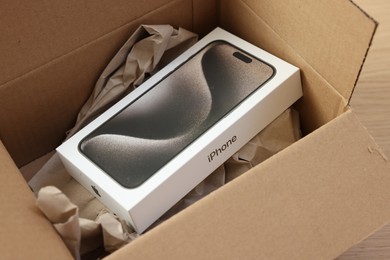 Leiden, Netherlands - October 6, 2023: New iPhone 15 Pro Max and crumpled paper in cardboard box on table, closeup. Amazon delivery