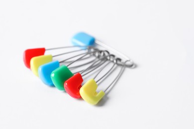 Photo of Colorful safety pins on white background, closeup. Space for text