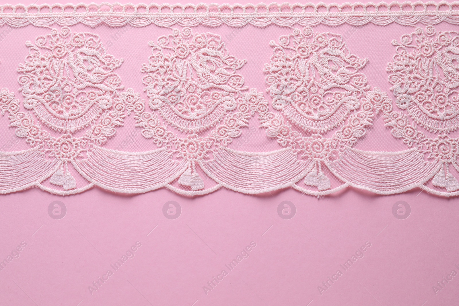 Photo of White lace on pink background, top view. Space for text