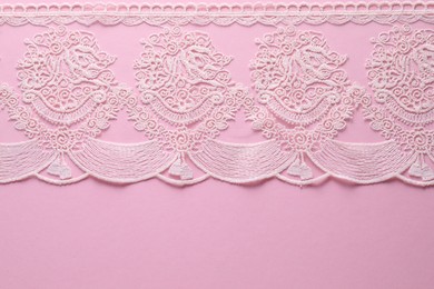 Photo of White lace on pink background, top view. Space for text