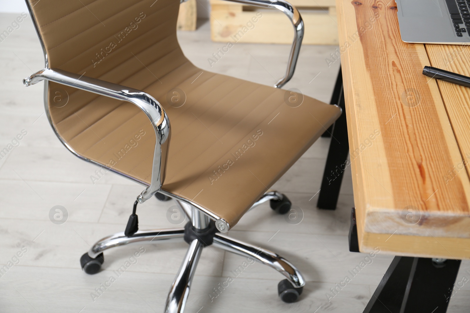 Photo of Comfortable workplace with office chair and wooden table, closeup
