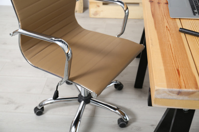 Photo of Comfortable workplace with office chair and wooden table, closeup