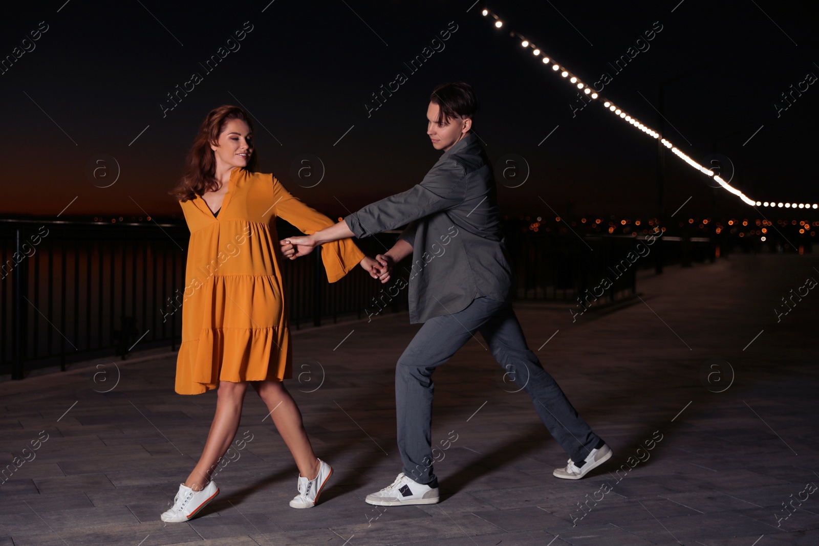 Photo of Beautiful young couple practicing dance moves in evening outdoors