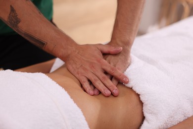 Photo of Woman receiving professional belly massage indoors, closeup